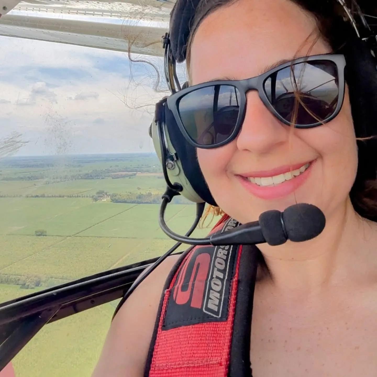 A brown haired woman in sunglasses, Manuela, on Ultralight flight over Valle del Cauca, at the runway where Manuela grew up watching her dad fly