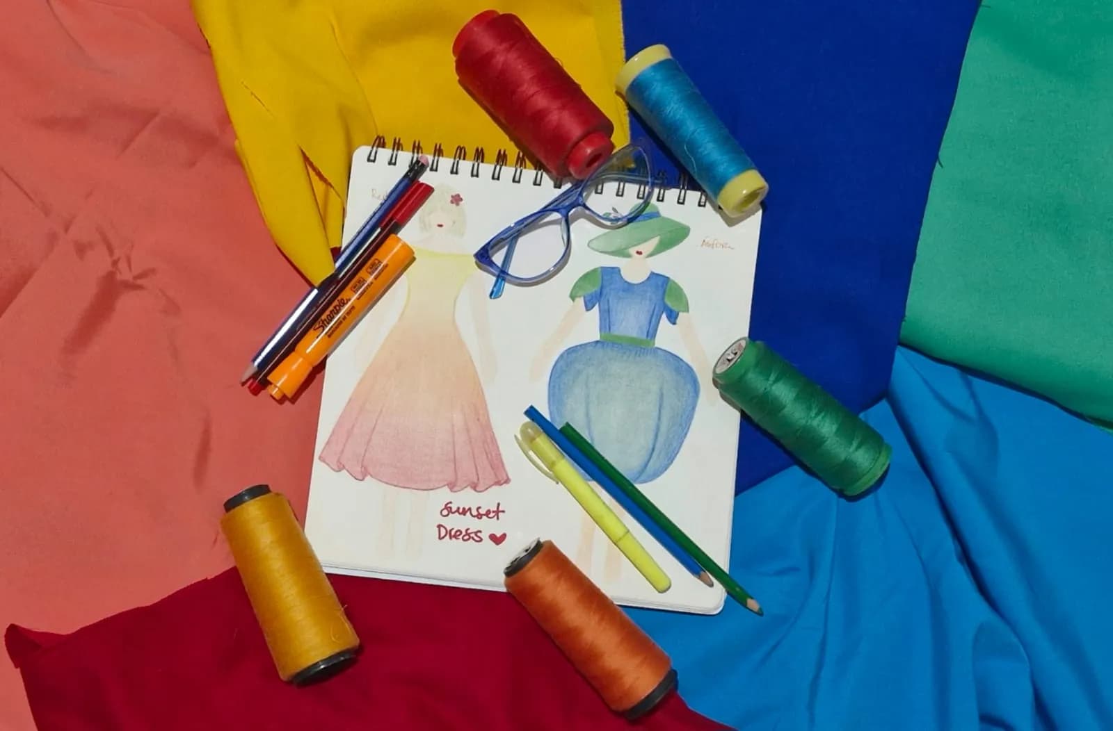 A notebook with dress designs, fabric and thread