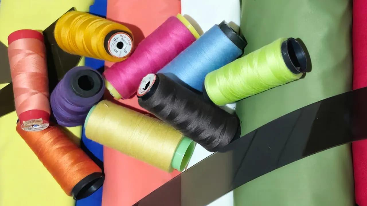 Colorful spools of thread laying on colorful fabric