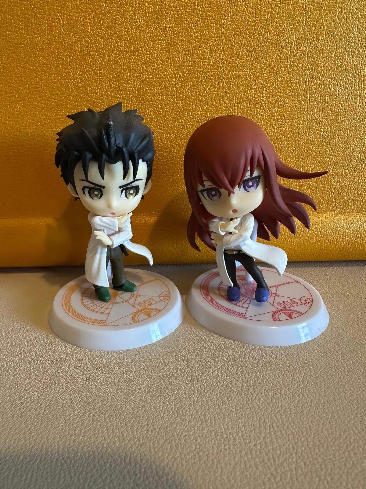 Two anime figurines in front of orange background